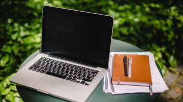 Defter ve belgelerle modern laptop çalışma alanı