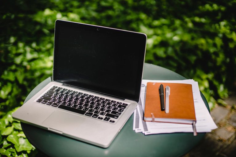 Defter ve belgelerle modern laptop çalışma alanı