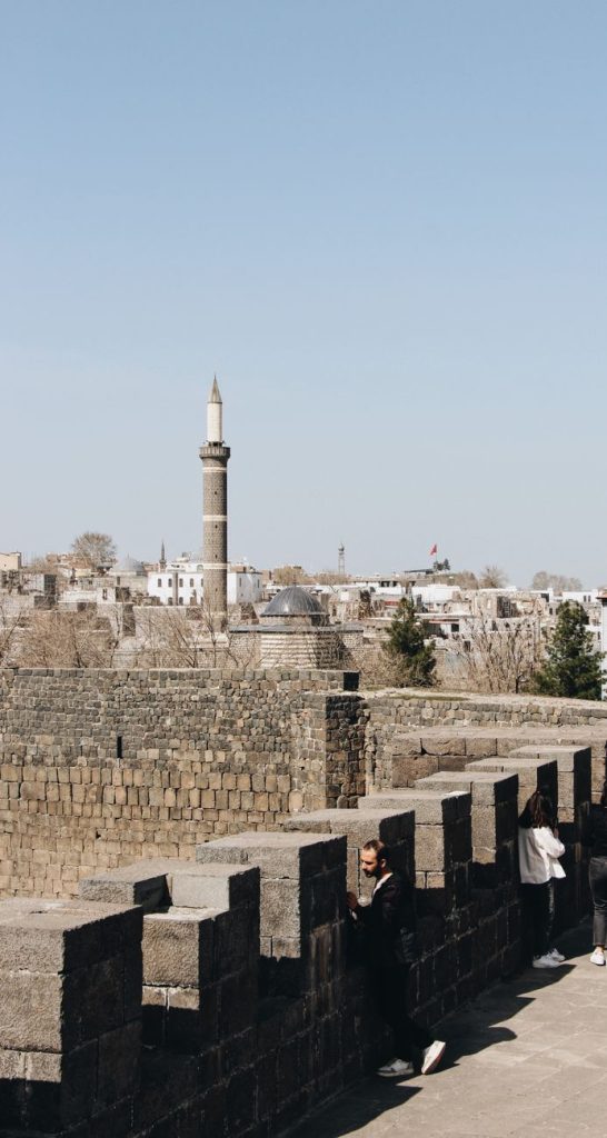 Açık gökyüzü altında öne çıkan bir minare ile antik bir şehir duvarının panoramik manzarası.