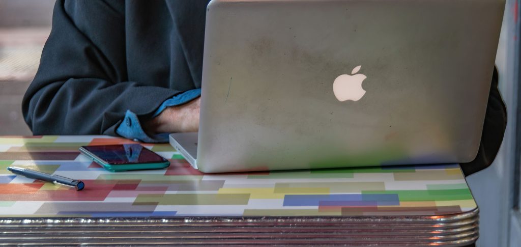 Renkli desenli bir masanın üzerinde birinin dizüstü bilgisayar ve akıllı telefon kullandığı yakın çekim.