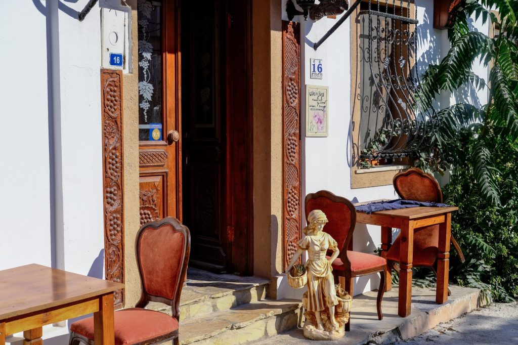 Bozcaada, Türkiye'deki bir kafenin önünde rustik ahşap mobilyalar, yaz güneşinin altında dekoratif bir figür ile.