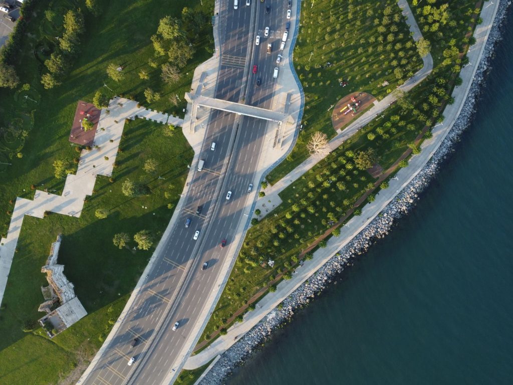 İstanbul, Türkiye'de canlı bir kıyı yolu ve parkın drone ile çekilmiş görüntüsü, yemyeşil doğa ve dinamik trafiği sergiliyor.