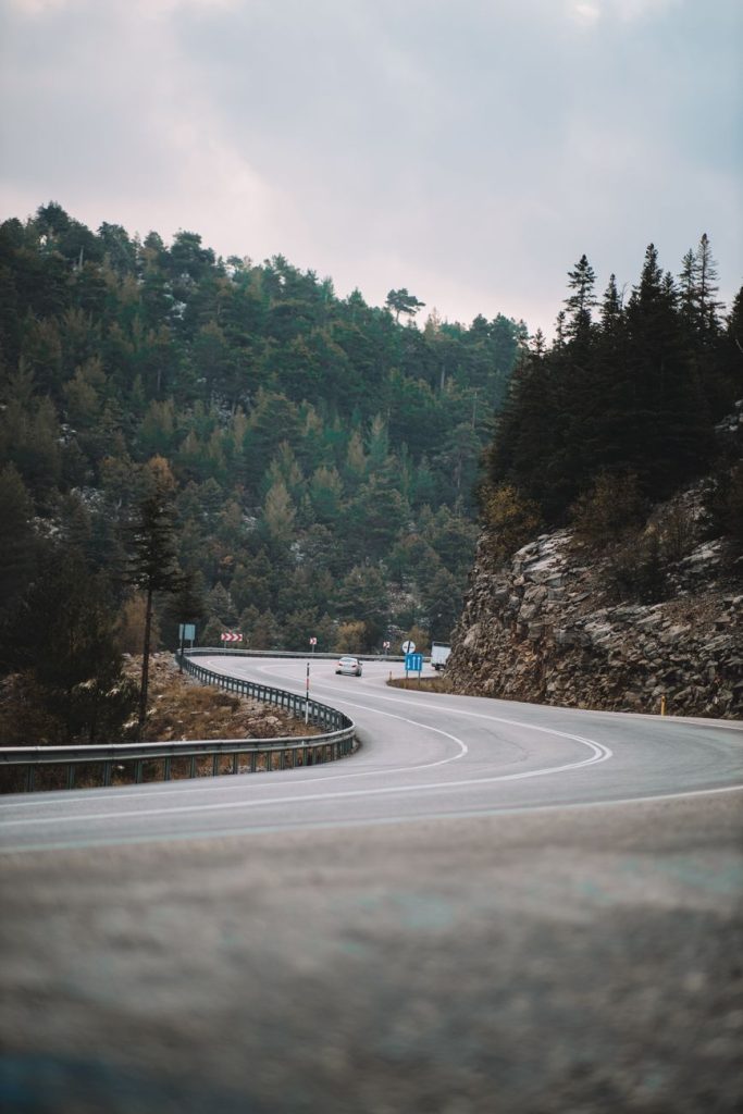 Sık ormanlarla çevrili dağlık arazide kıvrılan bir yol, seyahat ve macera temaları için ideal.