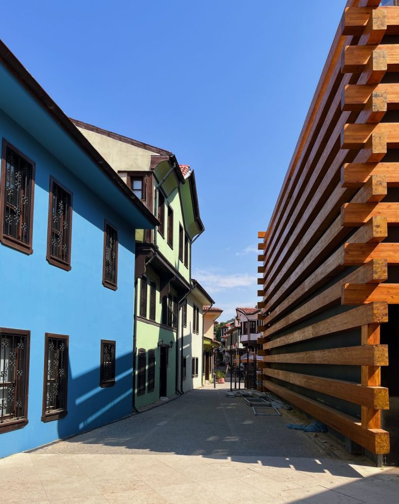 Açık mavi gökyüzü altında geleneksel ve modern mimari ile hareketli Eskişehir sokağı.