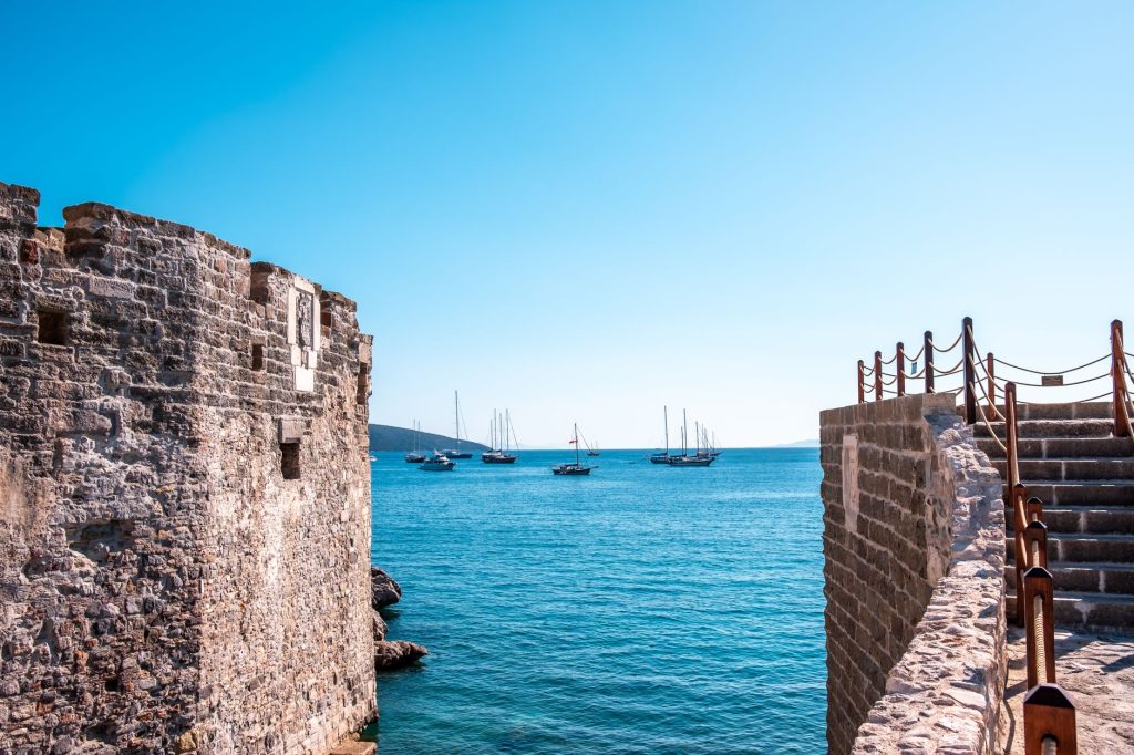 Açık gökyüzü altında Ege Denizi'ndeki yatlarla birlikte Bodrum Kalesi manzarası.