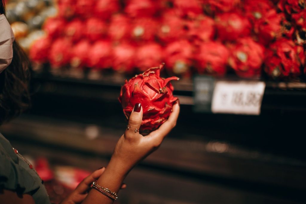 Market reyonunda ejder meyvesini inceleyen kişi