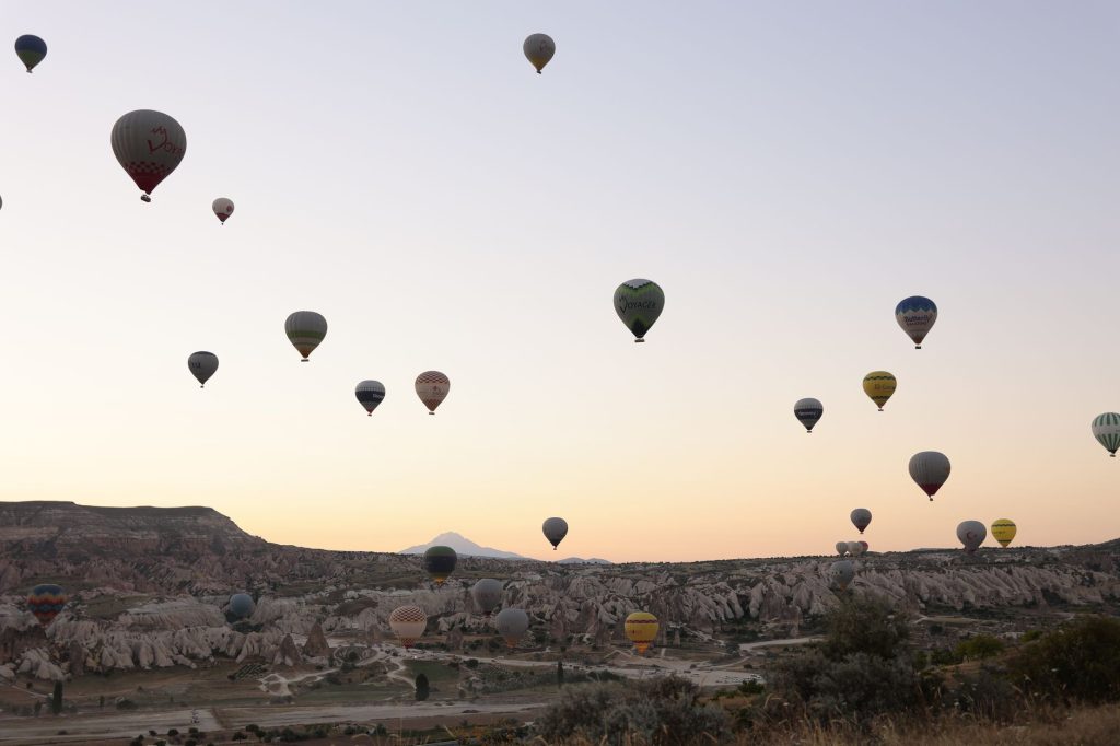 Kapadokya'nın eşsiz taş yapısı üzerinde renkli sıcak hava balonlarının sihirli manzarası, güneşin doğuşunda.