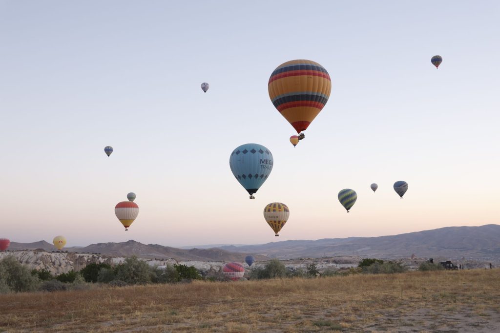 Sıcak hava balonları, gün doğumunda Türkiye'nin muhteşem manzarası Göreme'nin üzerinde zarifçe yükseliyor.
