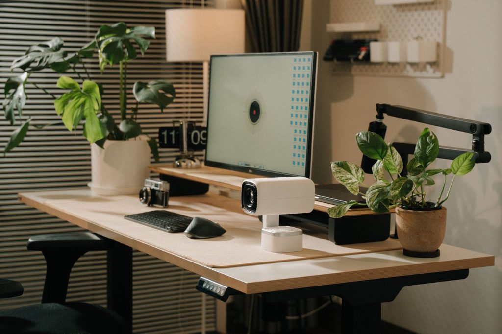 Ofis ortamında yeşillik, teknoloji ve şık dekorun bir arada olduğu modern bir masa düzeni.