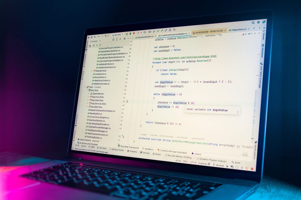 Karanlık bir ortamda görünür programlama kodu ile bir kod editörü gösteren bir dizüstü bilgisayar ekranı.