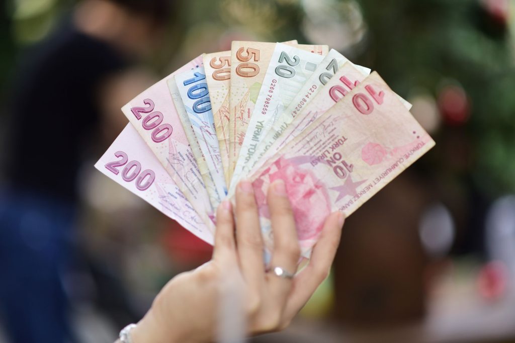 Açık havada bir el, Türk Lirası banknotlarının çeşitli değerlerini sergileyerek para birimi çeşitliliğini gözler önüne seriyor.