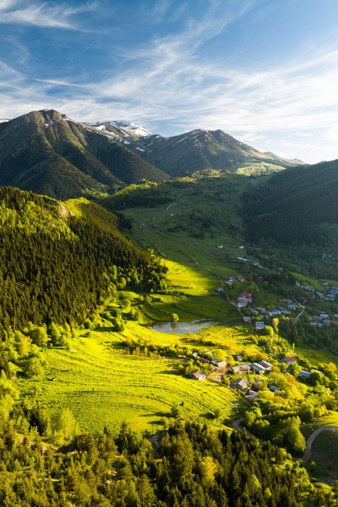 Bahar ışığında dağlar ve köylerle yemyeşil Artvin vadisinin nefes kesen kuşbakışı görüntüsü.