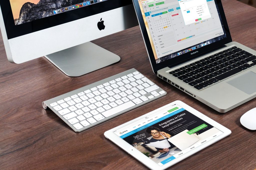 Apple cihazlarının bulunduğu şık bir ofis masa düzeni: iMac, MacBook ve iPad.