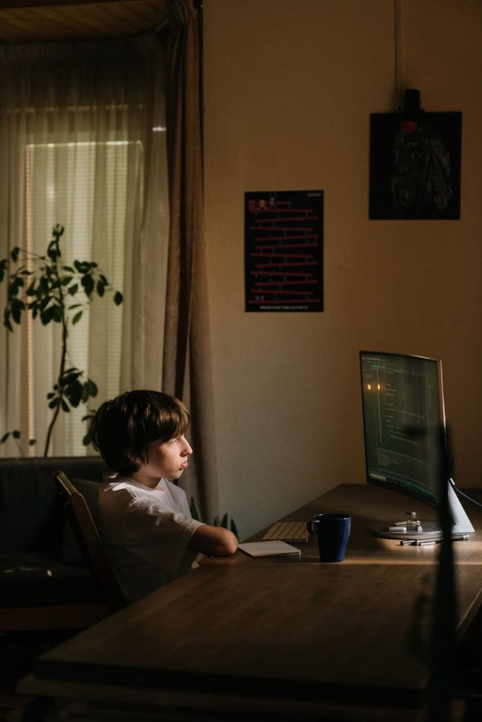 Evde bilgisayar programlamasına odaklanmış genç bir çocuk, teknoloji öğrenmeye dalmış.