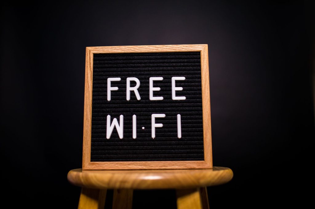 Karanlık bir odada bir sandalyenin üzerinde 'Ücretsiz Wi-Fi' yazılı ahşap çerçeve işareti.
