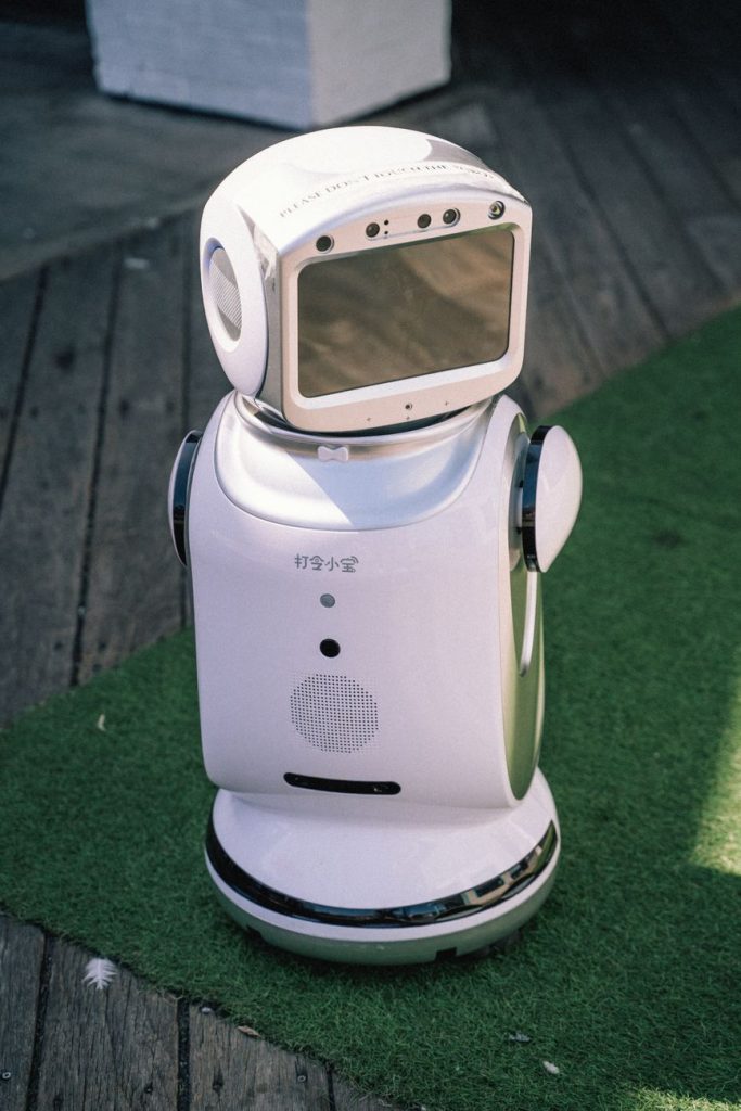Modern bir robot, çim ve ahşap zemin üzerinde durarak son teknoloji ürünlerini sergiliyor.